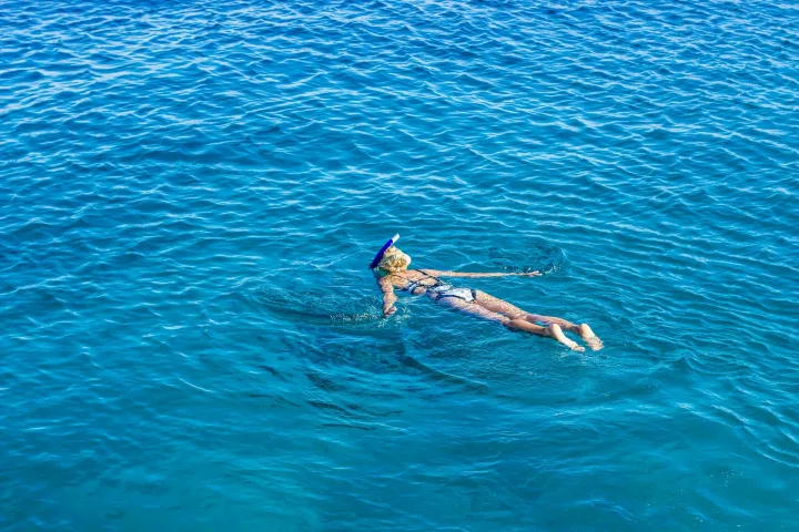 Eine Person beim Schnorcheln mit dem Gesicht nach unten im klaren blauen Wasser, von oben gesehen